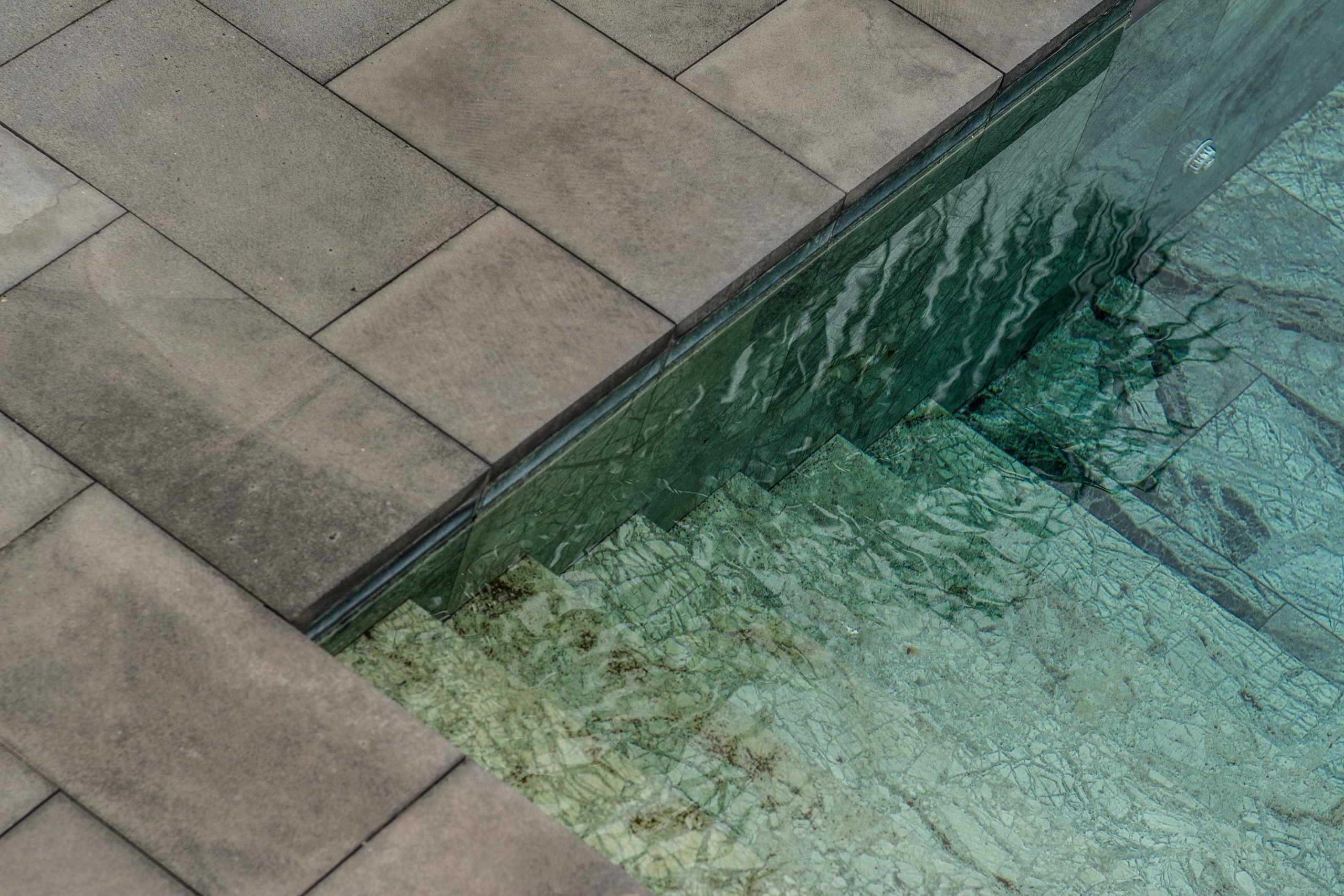 Inground fiberglass pool framed by paver decking
